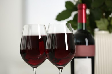 Glasses of delicious red wine on blurred background, closeup. Romantic date