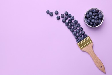 Creative flat lay composition with paint brush and blueberries on violet background. Space for text