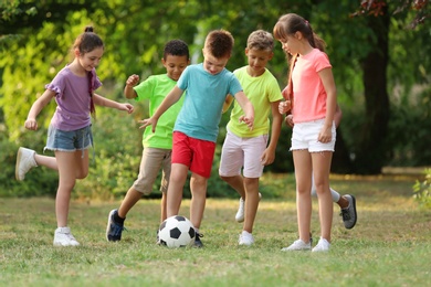 Cute little children playing with soccer ball in park