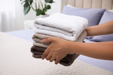 Woman putting Soft clean terry towels on bed, closeup