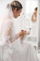 Young bride writing her single friends names on shoe indoors. Wedding superstition