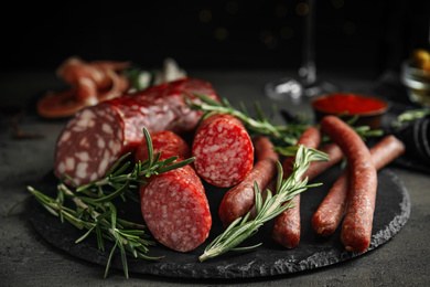 Different types of sausages with rosemary on grey table