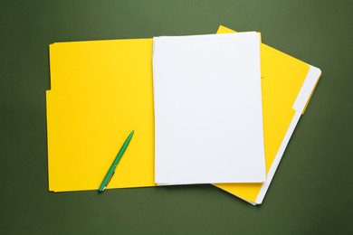 Yellow files with blank sheets of paper and pen on dark green background, top view. Space for design