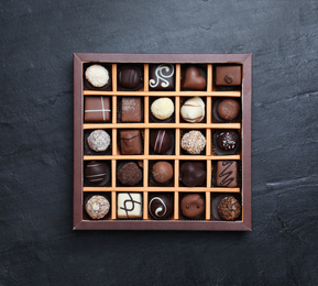Box with delicious chocolate candies on black table, top view