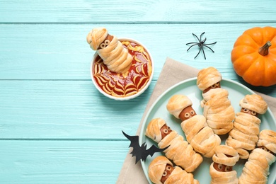 Spooky sausage mummies for Halloween party served on light blue wooden table, flat lay. Space for text