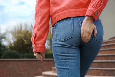 Woman suffering from hemorrhoid pain outdoors, closeup