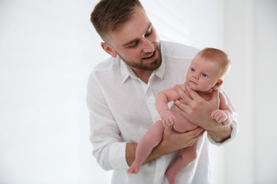 Father with his newborn son on light background