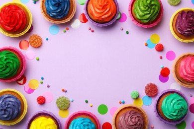 Frame of delicious colorful cupcakes and confetti on violet background, flat lay. Space for text