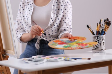 Woman artist drawing picture on canvas indoors, closeup