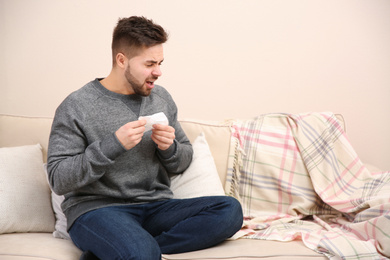 Sick young man sneezing at home. Influenza virus