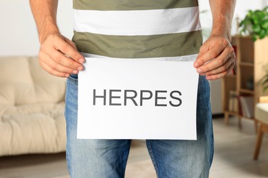 Photo of Man holding paper with word Herpes indoors, closeup
