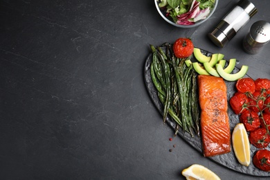 Photo of Tasty cooked salmon and vegetables served on black table, flat lay with space for text. Healthy meals from air fryer