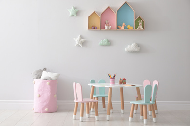 House shaped shelves and little table with chairs in children's room. Interior design
