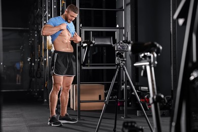 Photo of Man showing his abs on camera at gym. Online fitness trainer