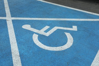 Photo of Wheelchair symbol on asphalt road. Disabled parking permit