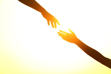 Silhouettes of man and woman helping each other against sunset, closeup