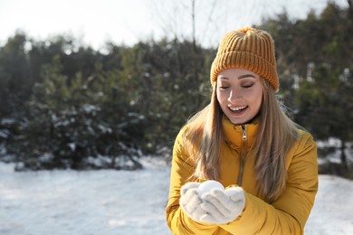 Woman holding snowball outdoors on winter day, space for text