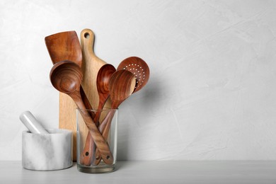 Set of kitchen utensils, board and mortar with pestle on white wooden table. Space for text