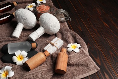 Photo of Herbal massage bags and other spa products on wooden table, space for text