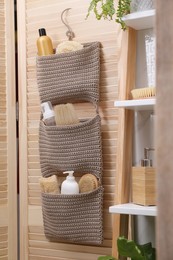 Storage with essentials hanging on wooden folding screen in bathroom. Stylish accessory
