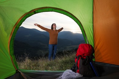 Photo of Young woman in mountains, view from camping tent