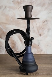 Beautiful traditional hookah on wooden table against light background