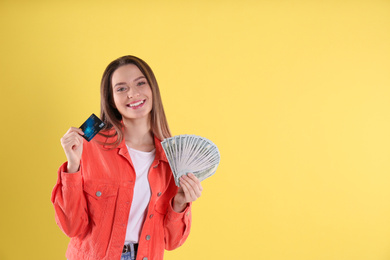 Young woman with money and credit card on yellow background. Space for text