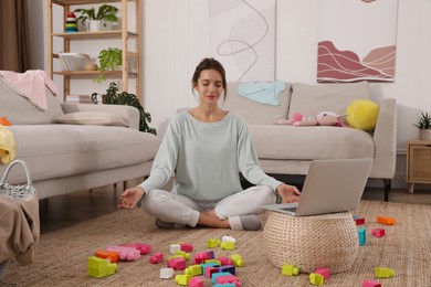 Young mother meditating on floor in messy living room