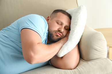 Lazy overweight man sleeping on sofa at home