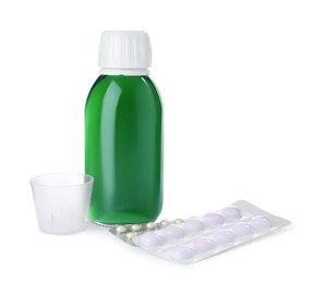 Photo of Bottle of syrup, measuring cup with pills on white background. Cough and cold medicine