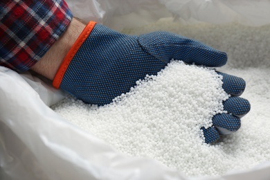 Farmer taking pellets of ammonium nitrate from bag, closeup. Mineral fertilizer