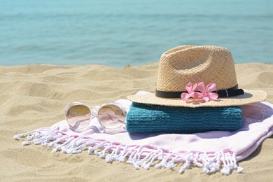 Photo of Stylish beach accessories and flowers on sand near sea