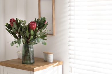 Photo of Vase with beautiful Protea flowers on table indoors