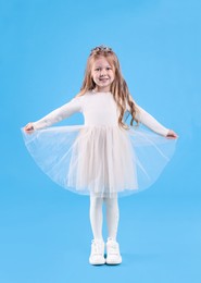 Cute girl in beautiful dress with diadem on light blue background. Little princess