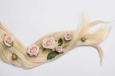 Photo of Lock of healthy blond hair with flowers on white background, top view