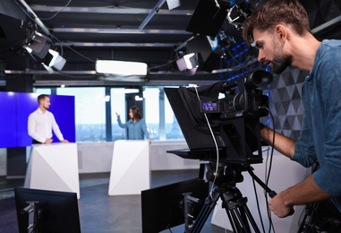 Presenters and video camera operator working in studio. News broadcasting