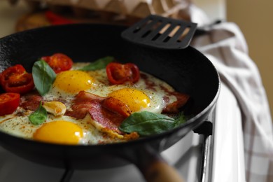 Delicious fried eggs with bacon and tomatoes in pan, closeup