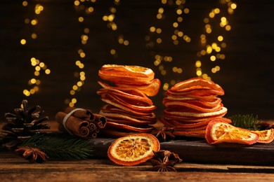 Photo of Dry orange slices, anise stars and cinnamon sticks on wooden table. Bokeh effect