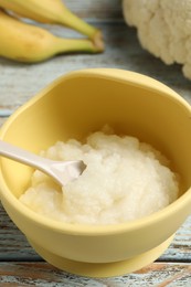 Photo of Baby food. Bowl with cauliflower puree and ingredients on rustic wooden table, closeup