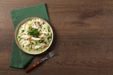Photo of Delicious salad with Chinese cabbage, crab sticks and parsley on wooden table, top view. Space for text