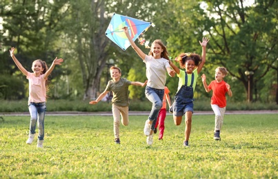 Photo of Cute little children playing with kite outdoors on sunny day