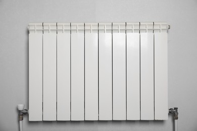 Modern heating radiator on light wall indoors