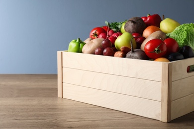 Crate full of different vegetables and fruits on wooden table. Harvesting time