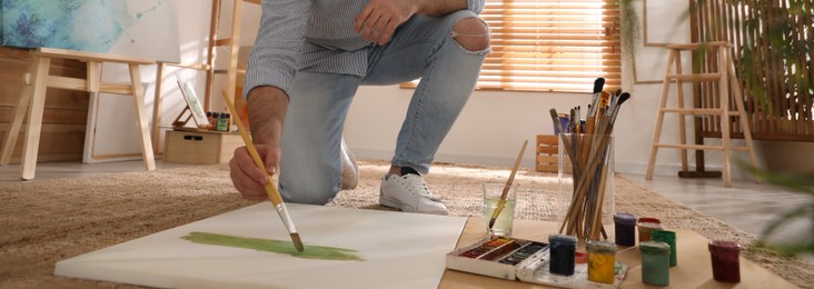 Young man painting with brush in artist studio, closeup. Banner design