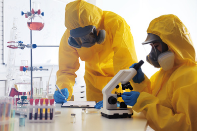 Scientists in chemical protective suits working at laboratory. Virus research