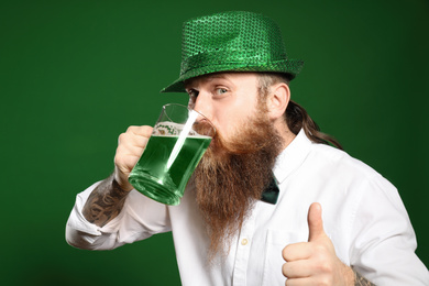 Bearded man drinking green beer on color background. St. Patrick's Day celebration