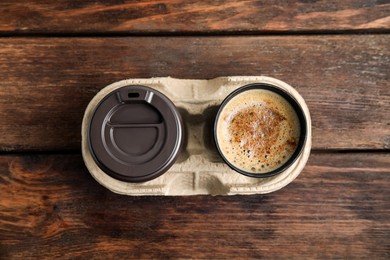 Takeaway paper cups with coffee in cardboard holder on wooden table, top view