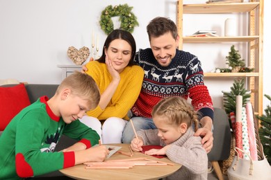 Cute children with their parents making beautiful Christmas greeting cards at home