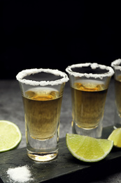 Mexican Tequila shots, lime slices and salt on grey table