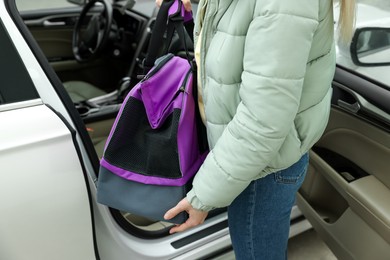 Woman putting pet carrier in car, closeup